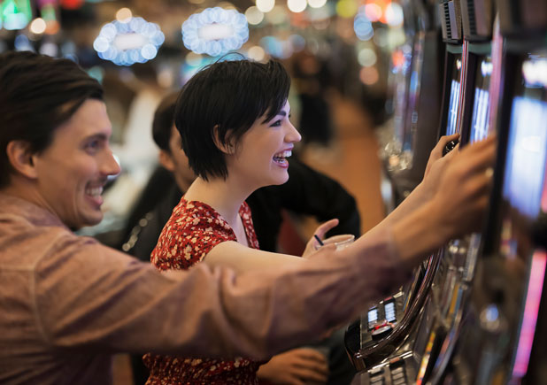 casino tourism trends - young couple playing slots - real action slots